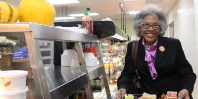 Congresswoman Beatty holds school lunch and smiles.