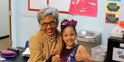 Image of Congresswoman Beatty giving thumbs up with a young child in school.