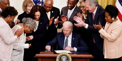 Image of Congresswoman Beatty smiling while watching President Biden sign the Juneteenth National Independence Day Act into law. 